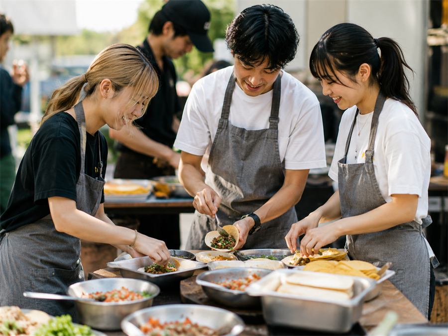 屋外でみんなでタコスを作っている様子